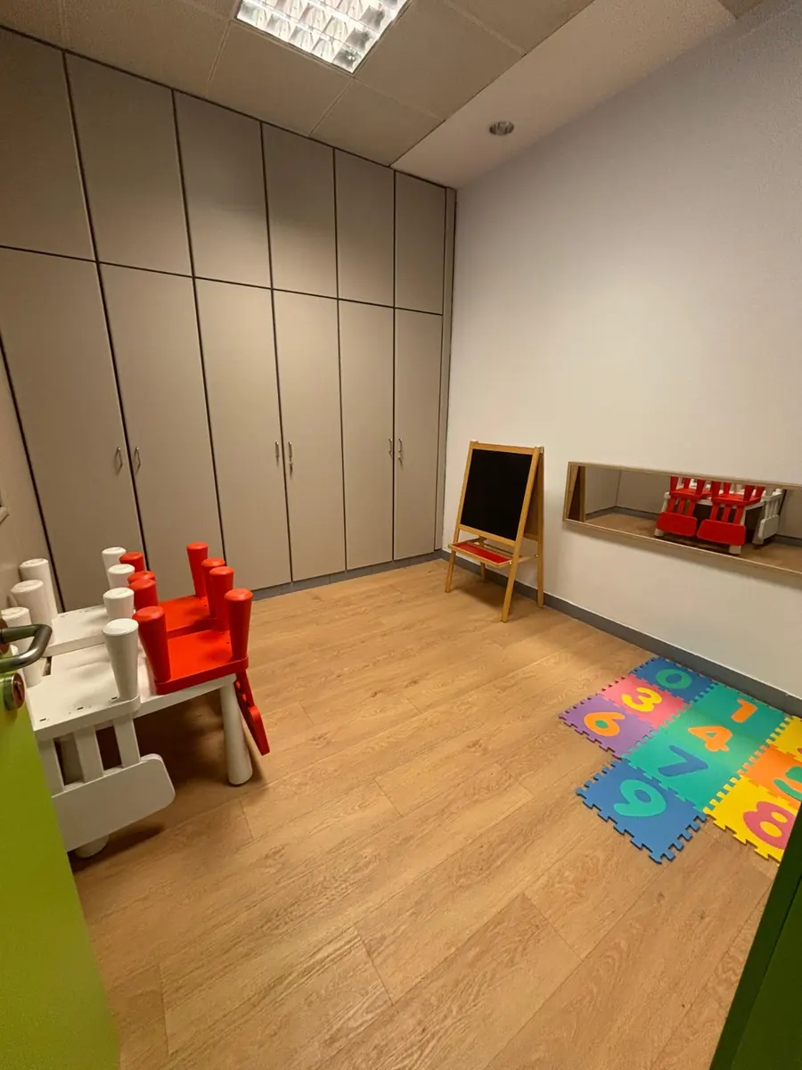 Sala de logopedia infantil con pizarra, espejo y alfombra de números